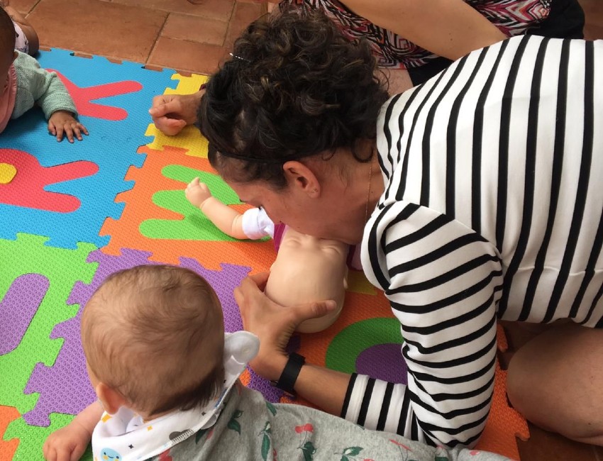 Mum performing CPR to a dummy beside her own baby